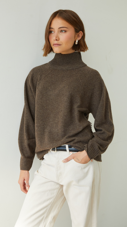 brown turtleneck sweater paired with cream trousers and a black belt