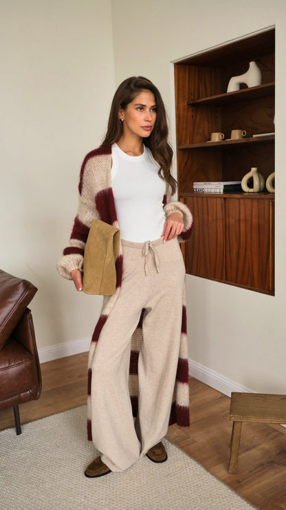 long striped cardigan in burgundy and beige over a white fitted tee, paired with beige wide-leg knit trousers