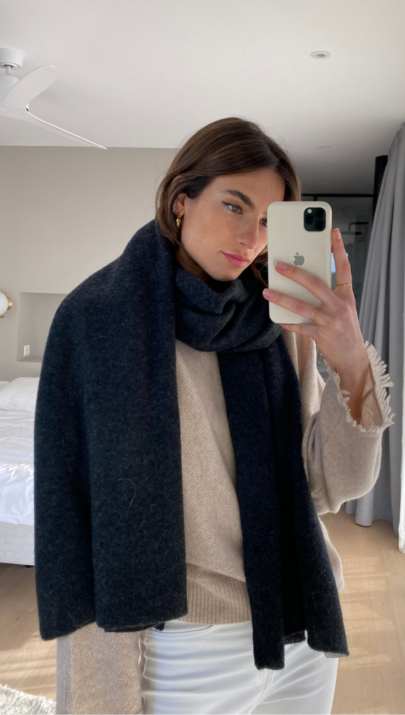 cosy beige sweater with frayed cuffs, a dark navy scarf, and white trousers
